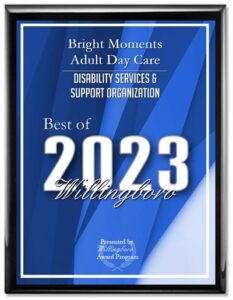 A plaque with a blue geometric background features the text: "Bright Moments Adult Day Care Disability Services & Support Organization, Best of 2023 Willingboro." Highlighting its excellence as an adult day care facility in Burlington County NJ, the plaque is presented by the Willingboro Award Program.